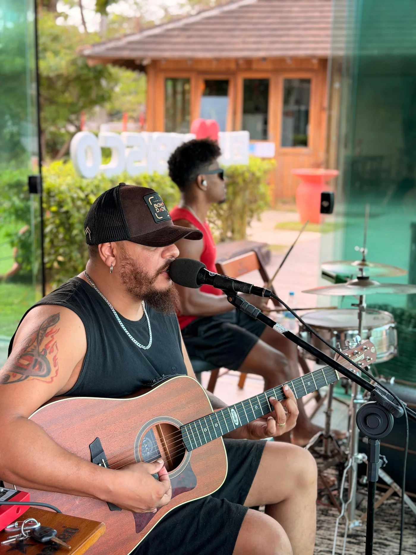 Cantor com violão acompanhado por percussionista no Hibisco Praia