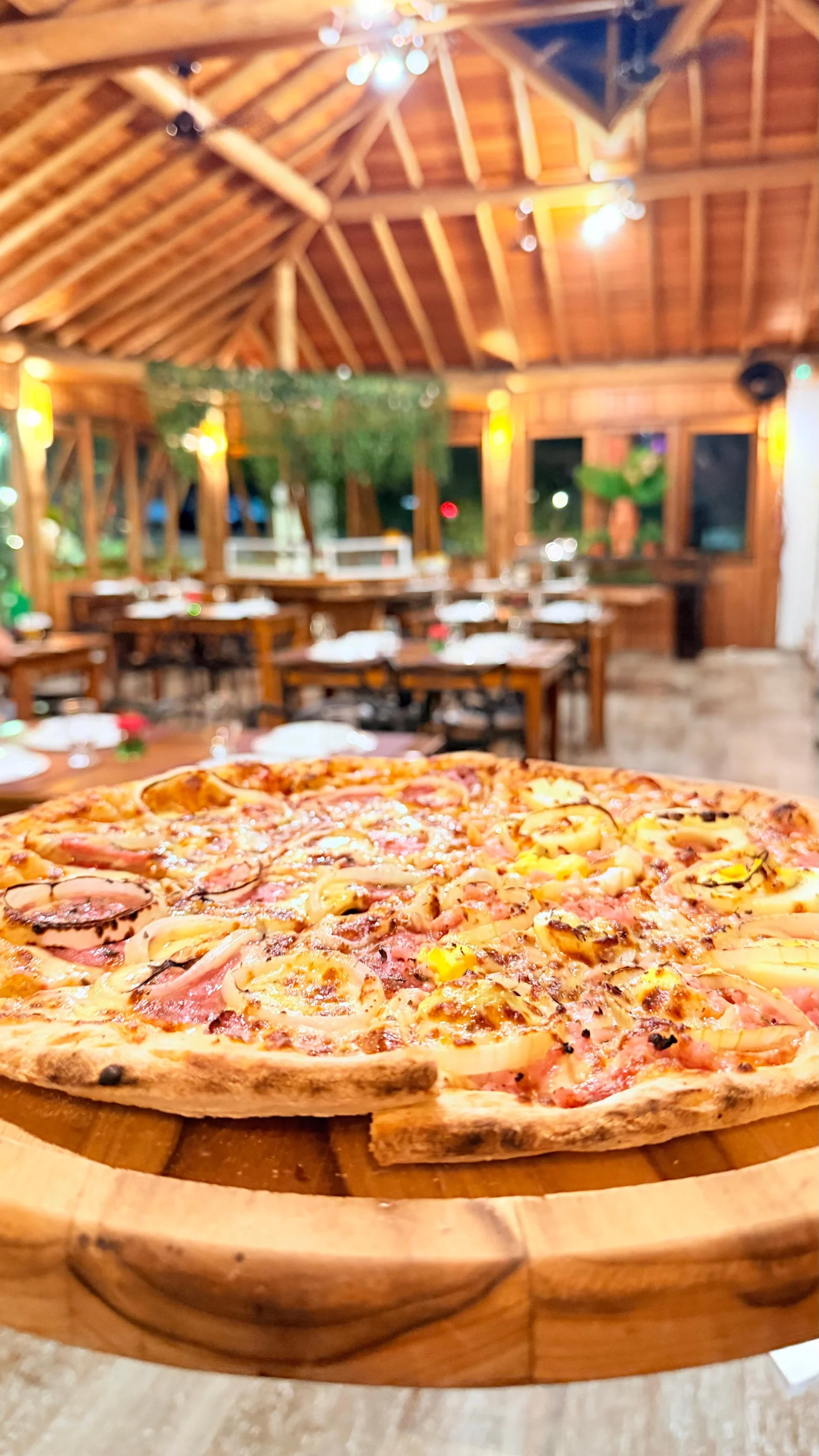 Pizza servida no salão de madeira do Hibisco Praia durante o jantar